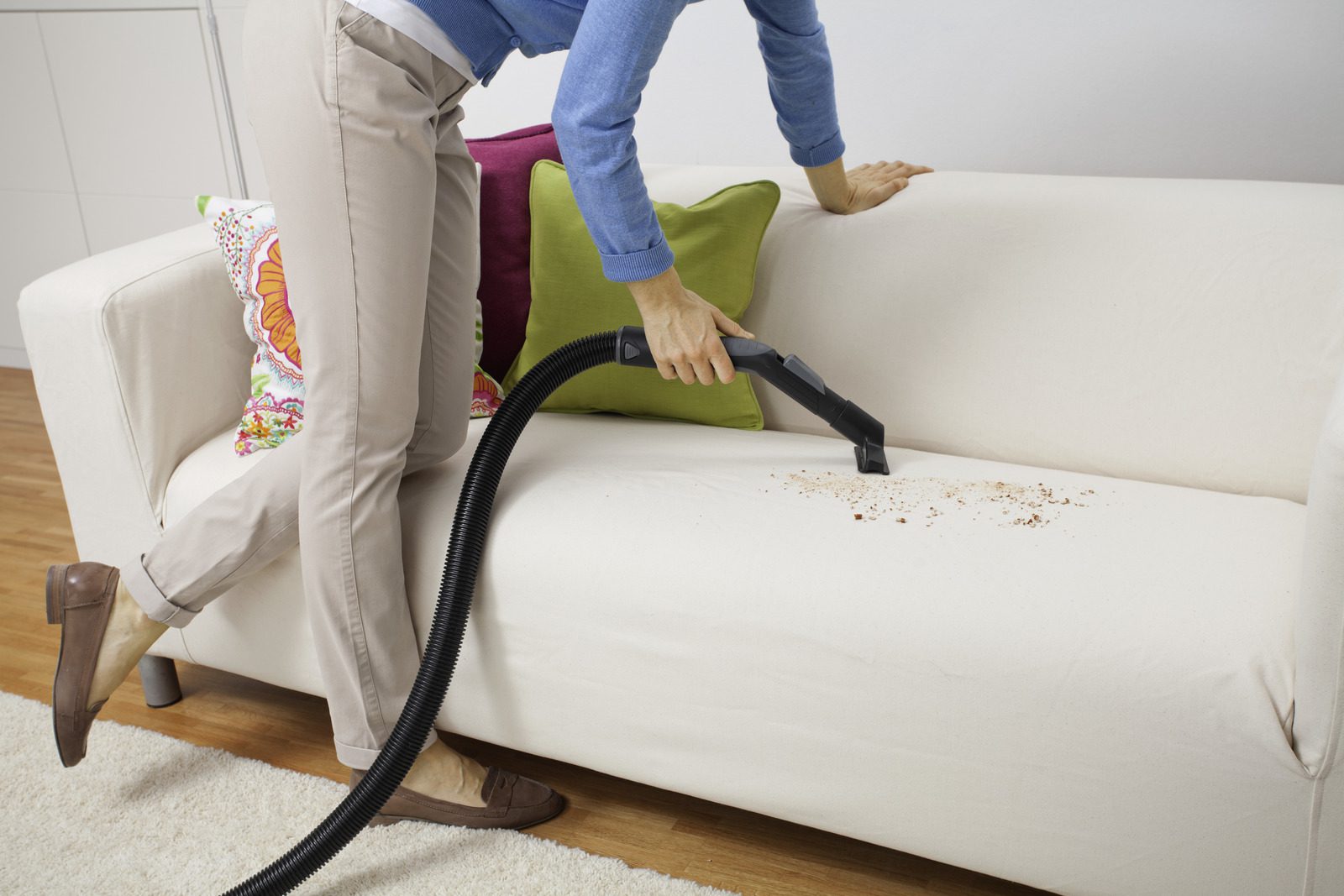 close shot of a person vacuum cleaning sofa.
