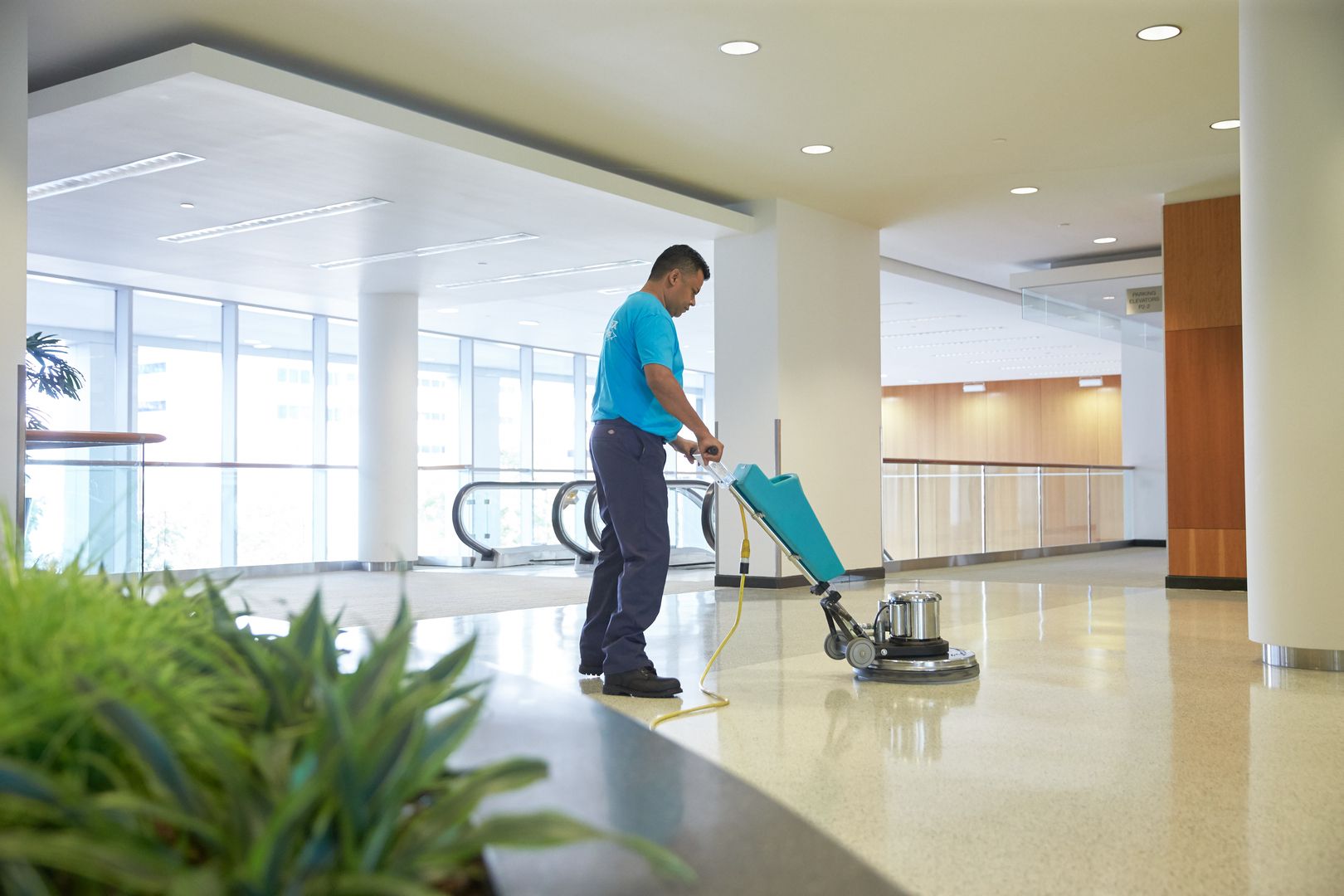 a cleaner polishing tiles with a scrubbing machine in a commercial building.