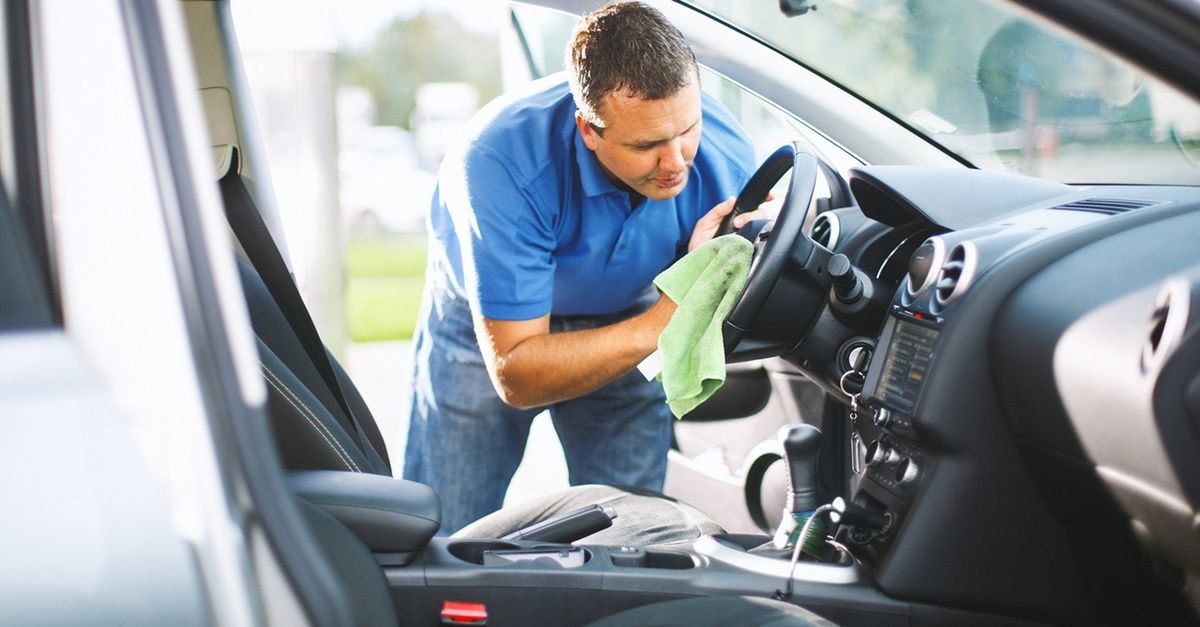 a professional man is cleaning car dashboard