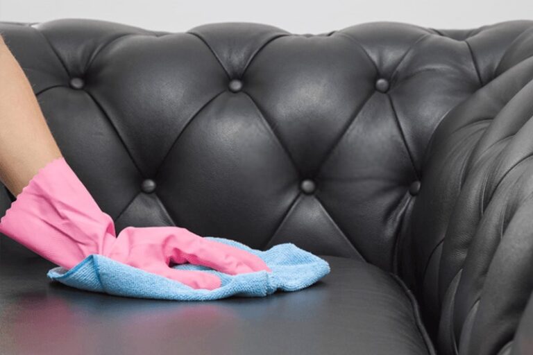 close shot of a hand cleaning black leather sofa.