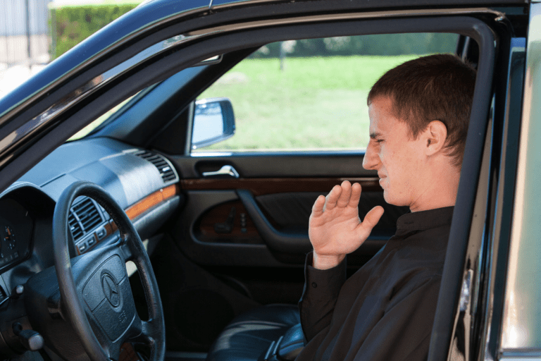 a man smelling something in his car