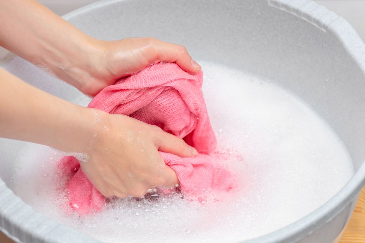 close shot of hands washing clothes in the bucket.