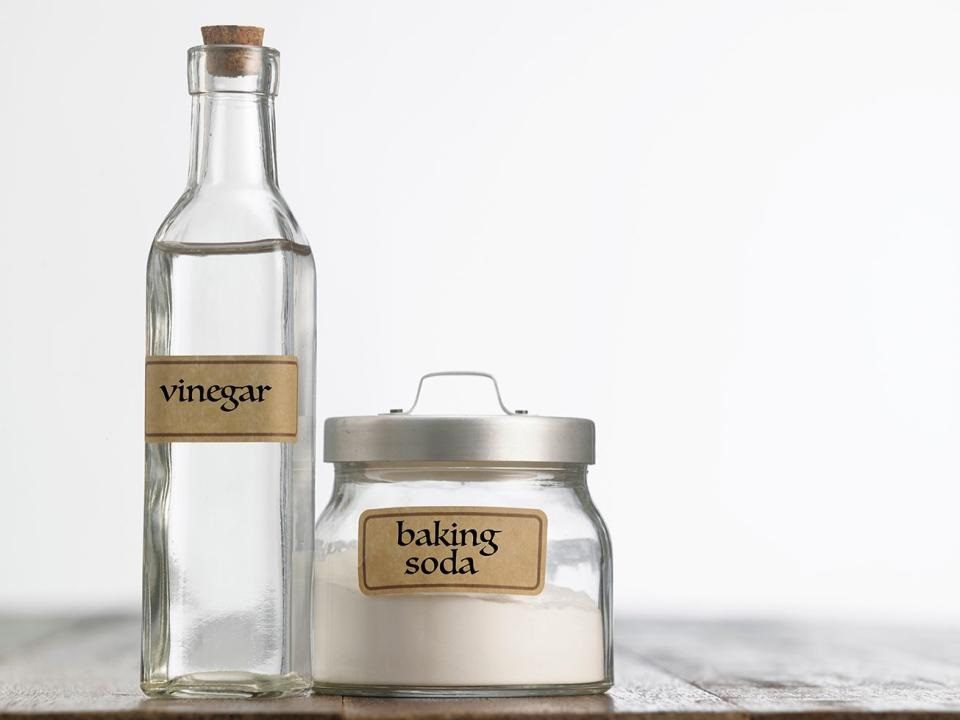 baking soda jar and vinegar bottle on a table surface.