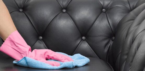 close shot of a hand cleaning black leather sofa.