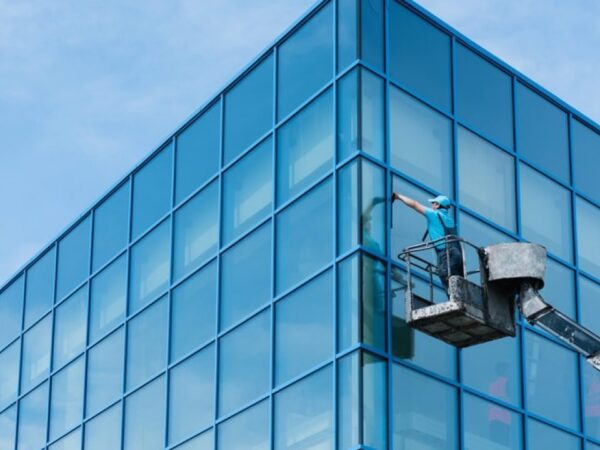 a guy on Crain cleaning windows of a blue color building