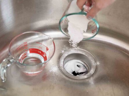 Baking soda and water are added to a garbage disposal for the cleaning process