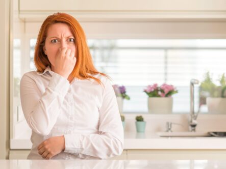 pinching her nose because of a bad smell in her house.